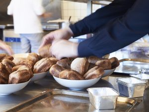 Tjener der portionerer små kuvertbrød